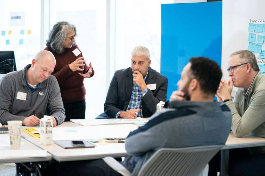 Adults at GVSU working together during a meeting around a table